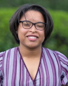 headshot of Leticia, a smiling Black woman in a purple shirt and glasses